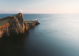 brown mountain cliff beside of blue ocean aerial photography