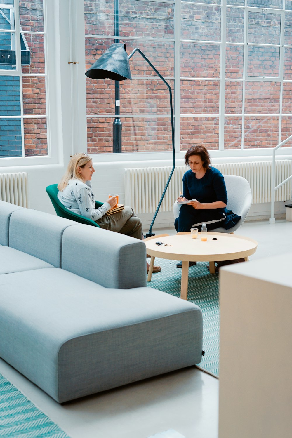 two woman sits on sofa chairs inside house