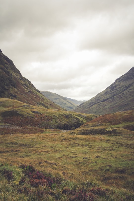 green grass field near mountain range during cloudy daytime in Glen Coe United Kingdom