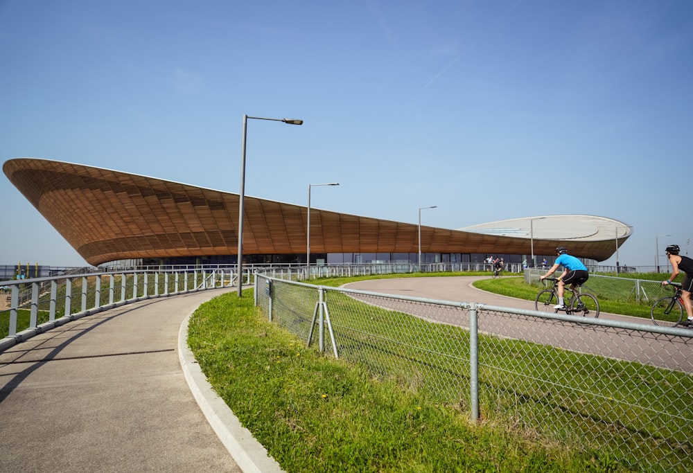 two cyclist on road near stadium at daytime