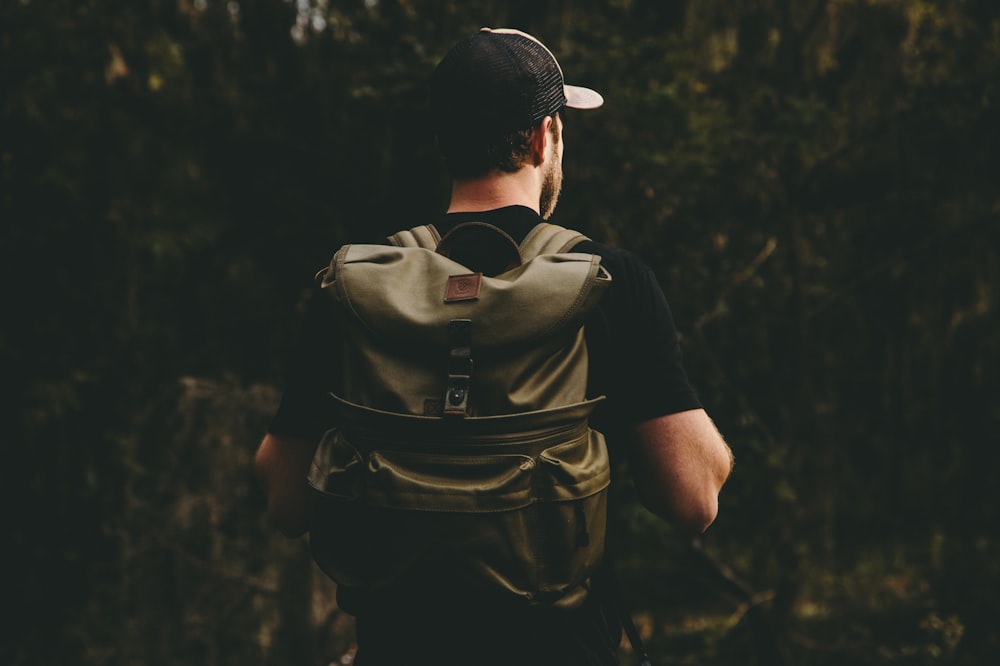 man at forest carrying brown backpack