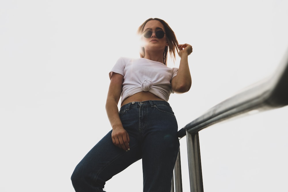 woman wearing white crop top and black pants standing near gray handrails during daytime