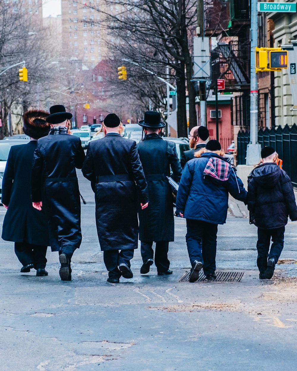昼間、歩道を歩く黒いコートを着た男性のグループ