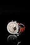 round silver-colored chronograph watch with brown leather strap