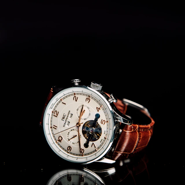 A round silver chronograph wristwatch on a brown leather strap