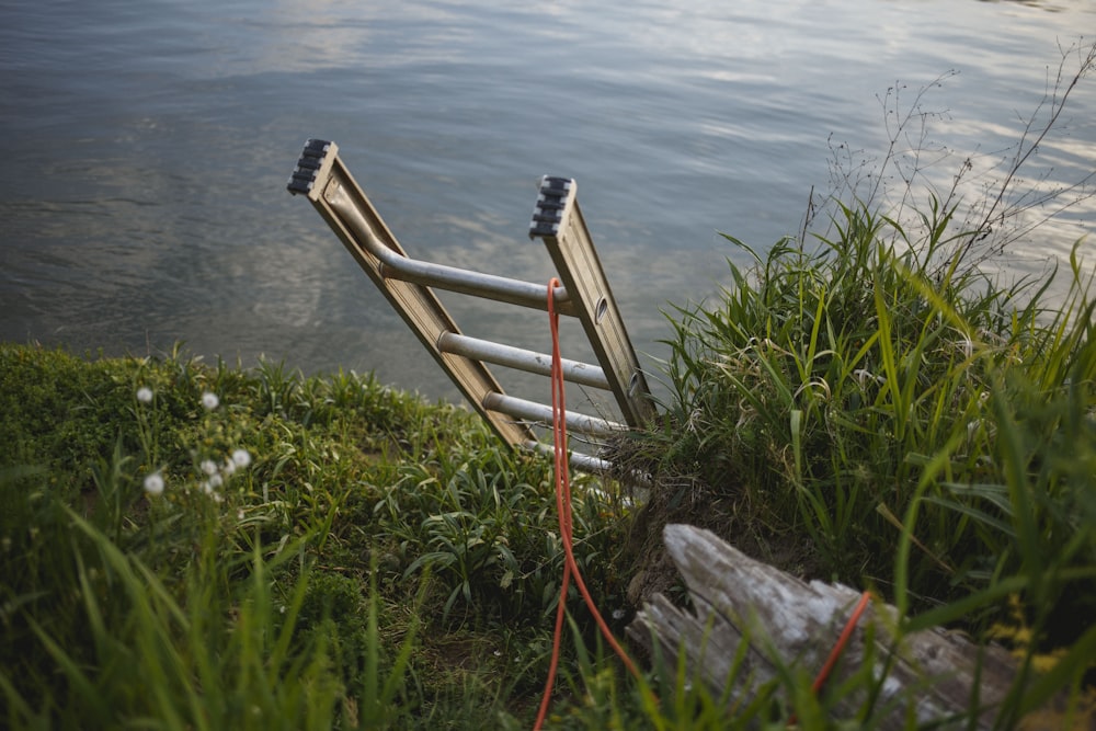 gray metal extension ladder on body of water leaning on soil surface