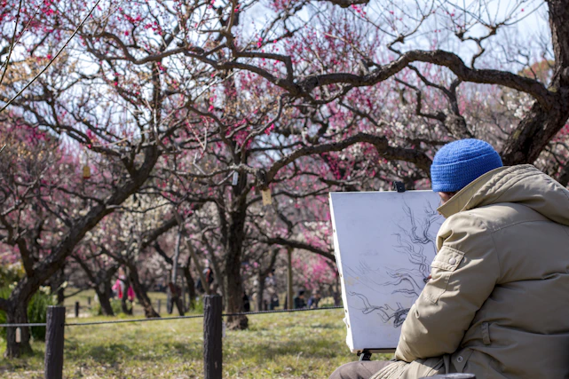 A person sketching in a sunny park, surrounded by nature and colorful art supplies.
