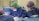 Several medical professionals are engaged in a surgical procedure. They are wearing surgical gowns, masks, caps, and gloves for hygiene and safety. The environment appears to be a sterile operating room with medical equipment around them.
