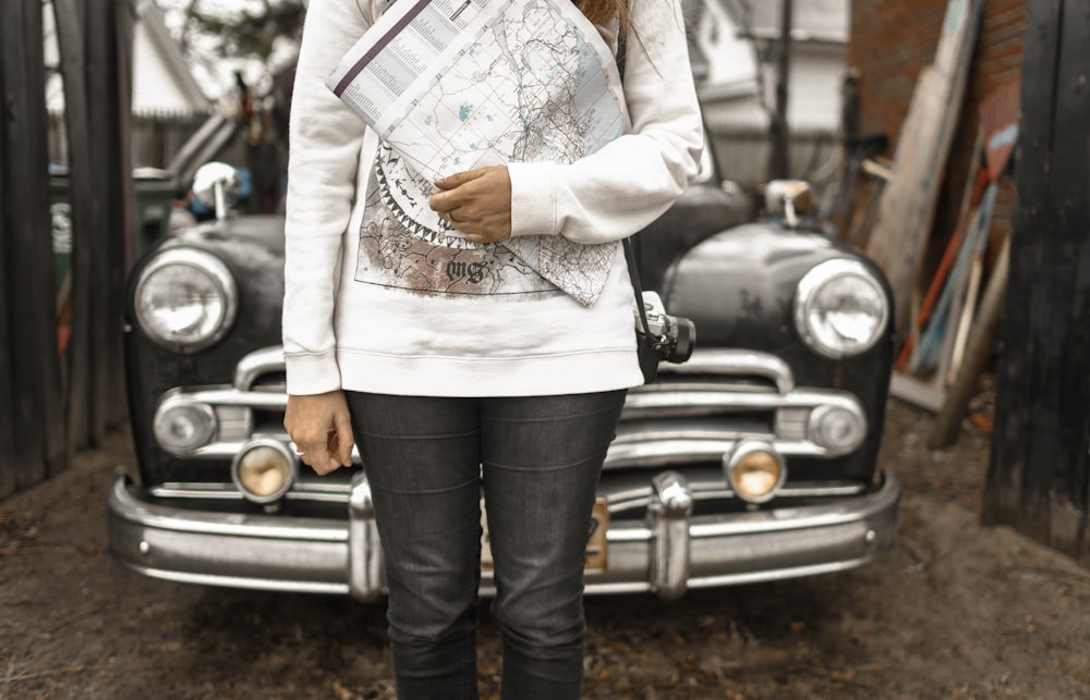 woman holding map standing on front of black vehicle