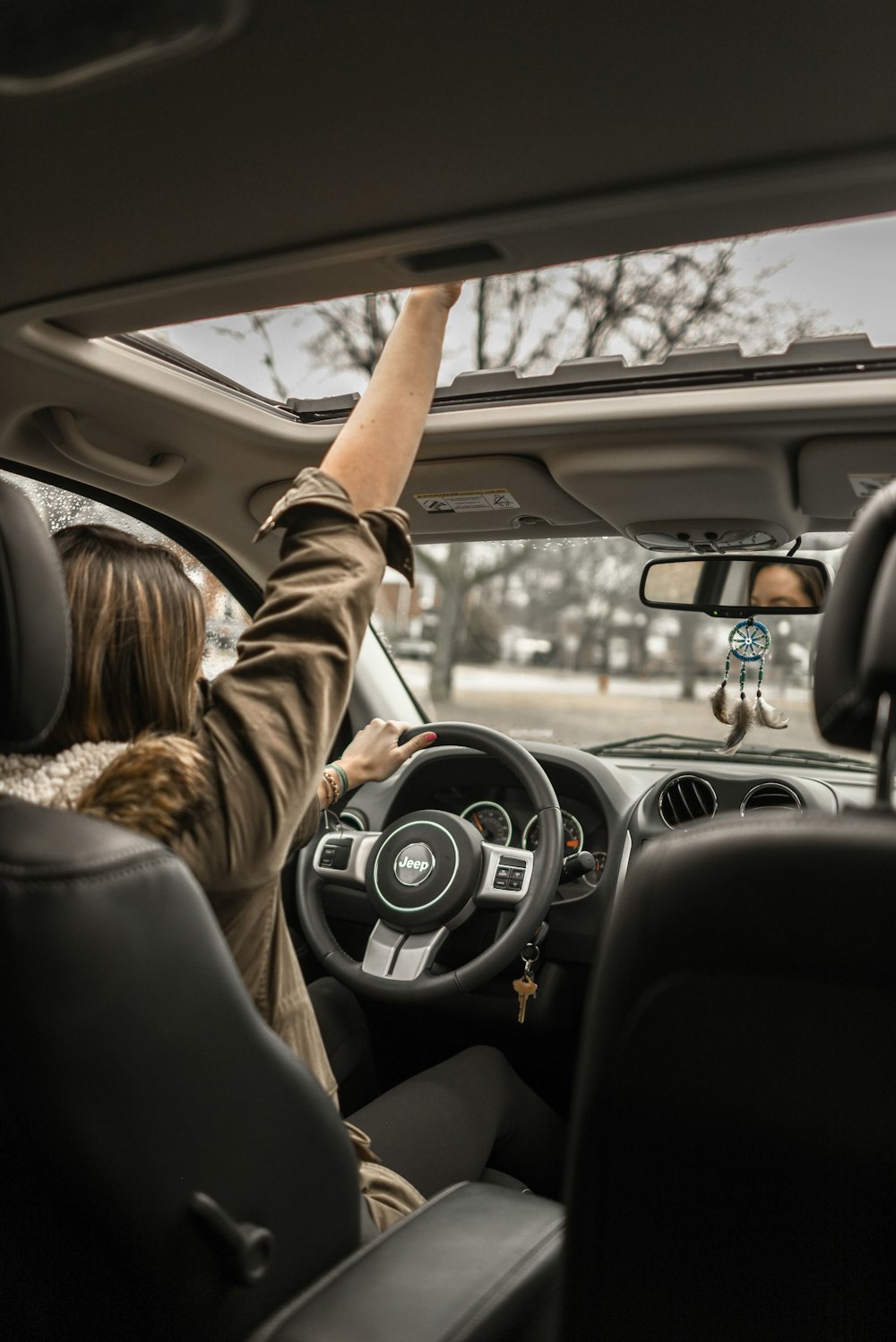 femme levant sa main droite à l’intérieur d’un véhicule noir et brun