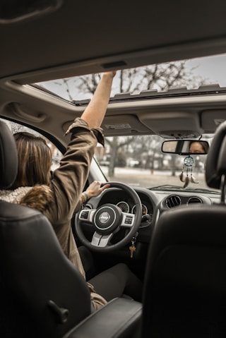 woman raising her right hand inside black and brown vehicle