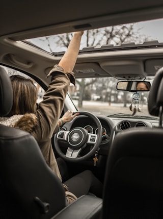 woman raising her right hand inside black and brown vehicle