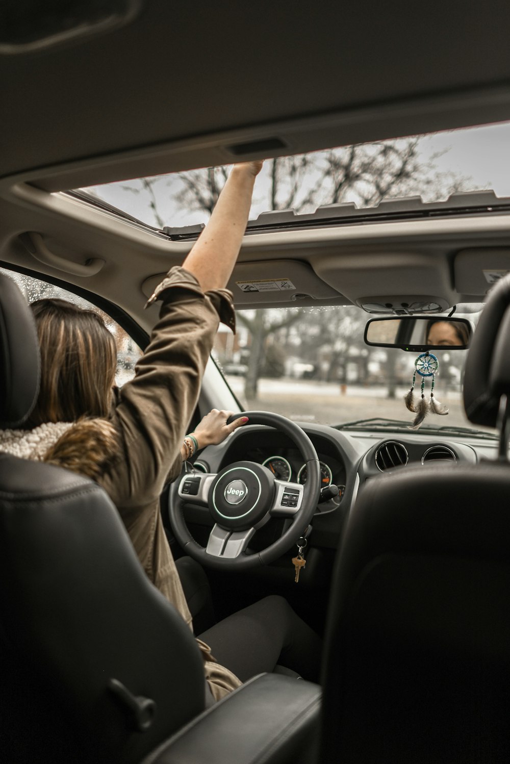 woman raising her right hand inside black and brown vehicle