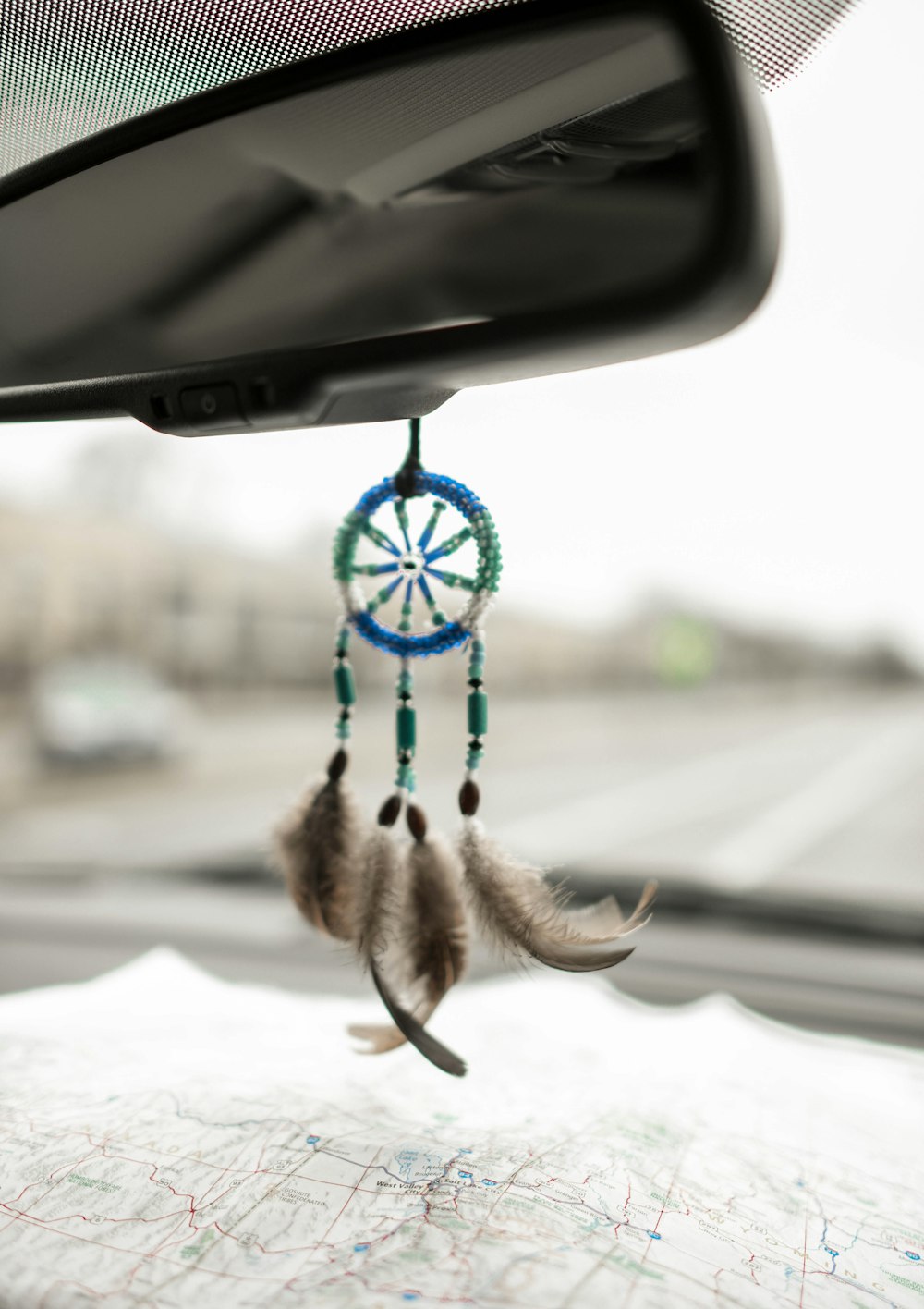 blue and green dream catcher hanging on black vehicle rear view mirror