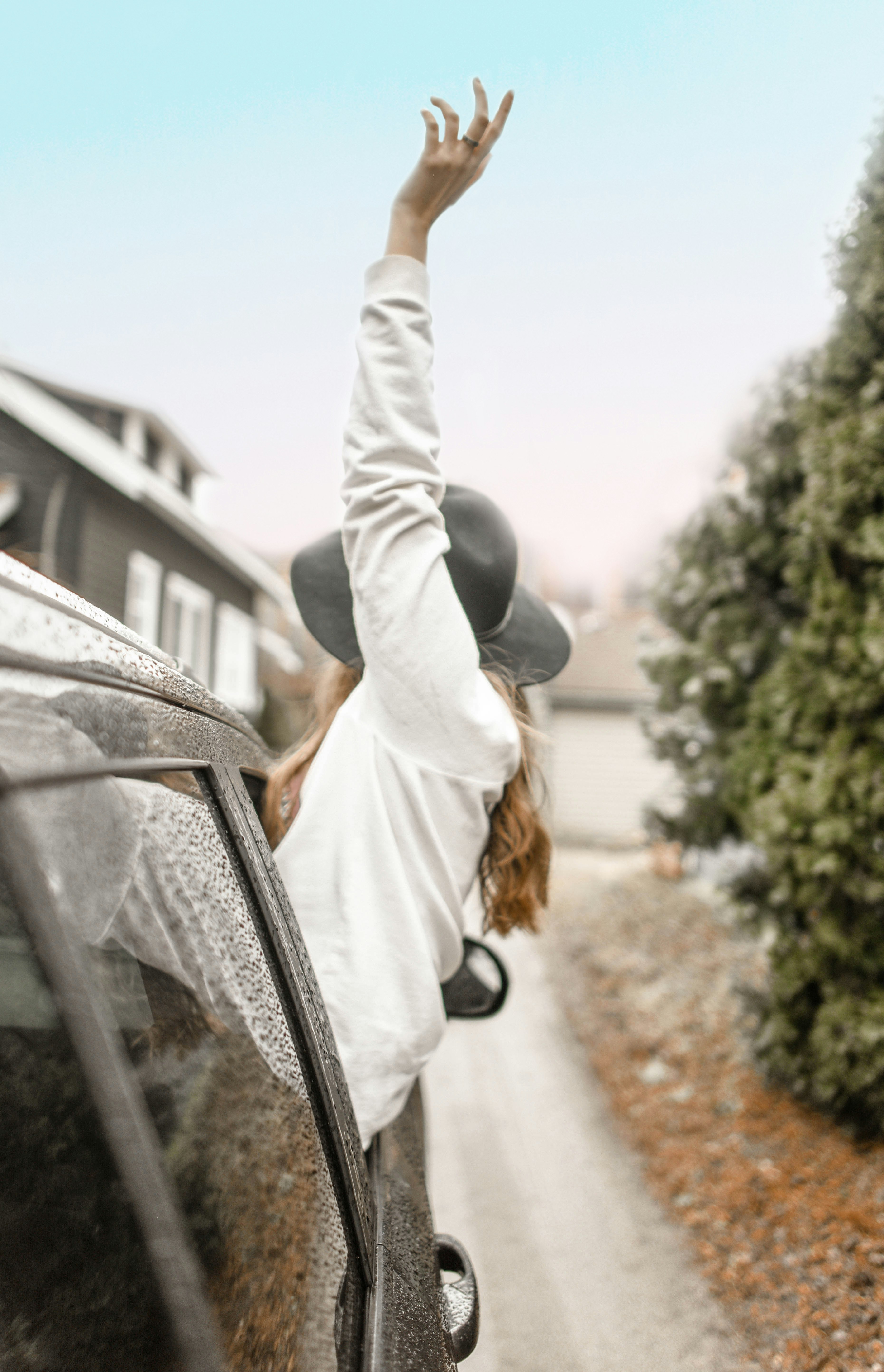 woman rising left hand on vehicle window during daytime