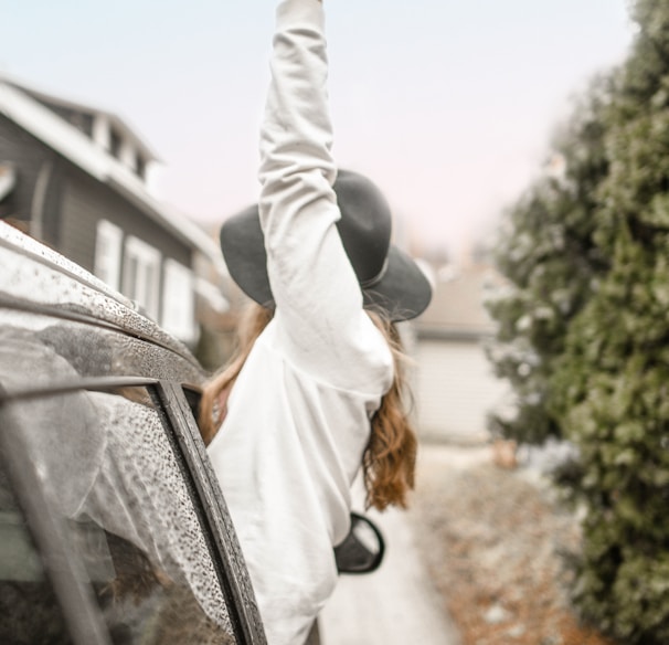 woman rising left hand on vehicle window during daytime