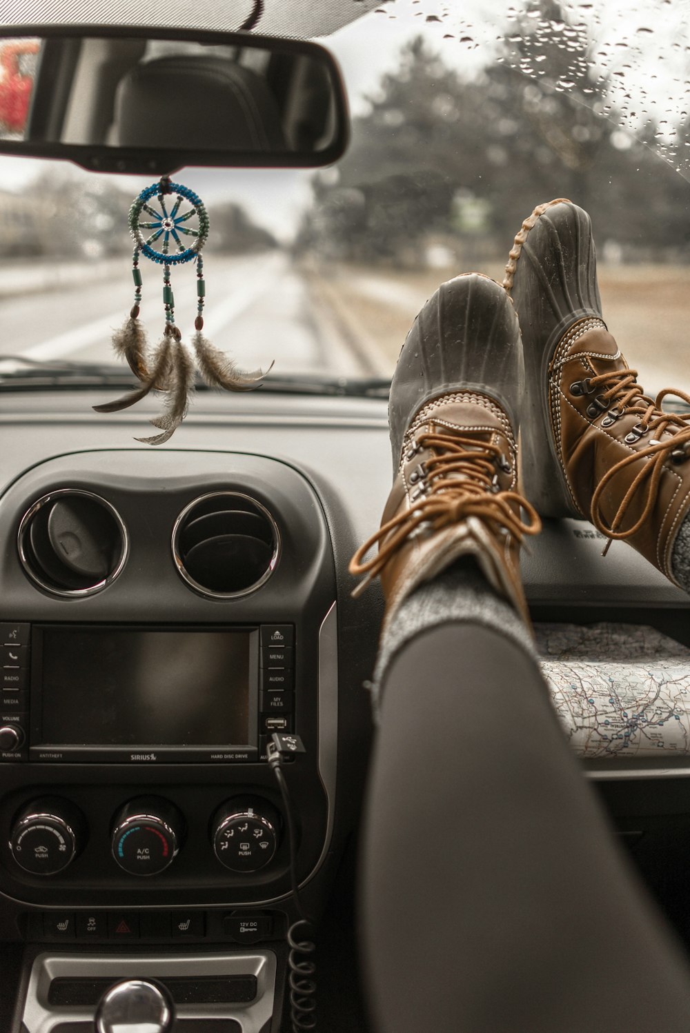 Person, die Entenstiefel trägt und ihre Stiefel auf das Handschuhfach des Fahrzeugs legt