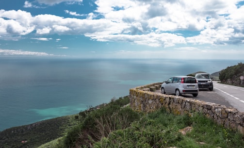 A comfortable rental car parked beside a winding coastal road with ocean views
