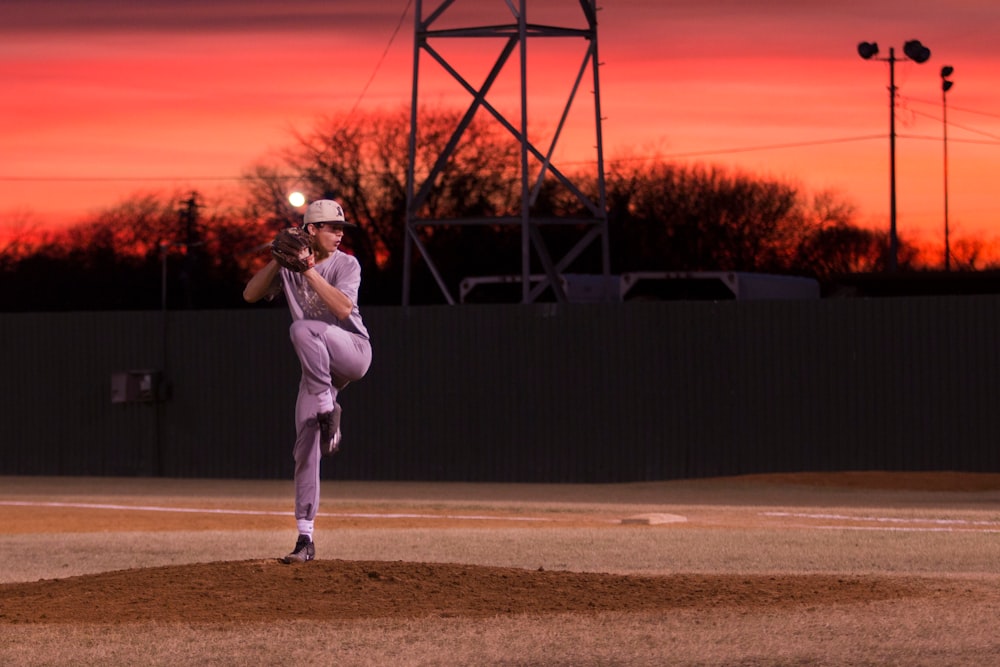 man pitching baseball during sunset