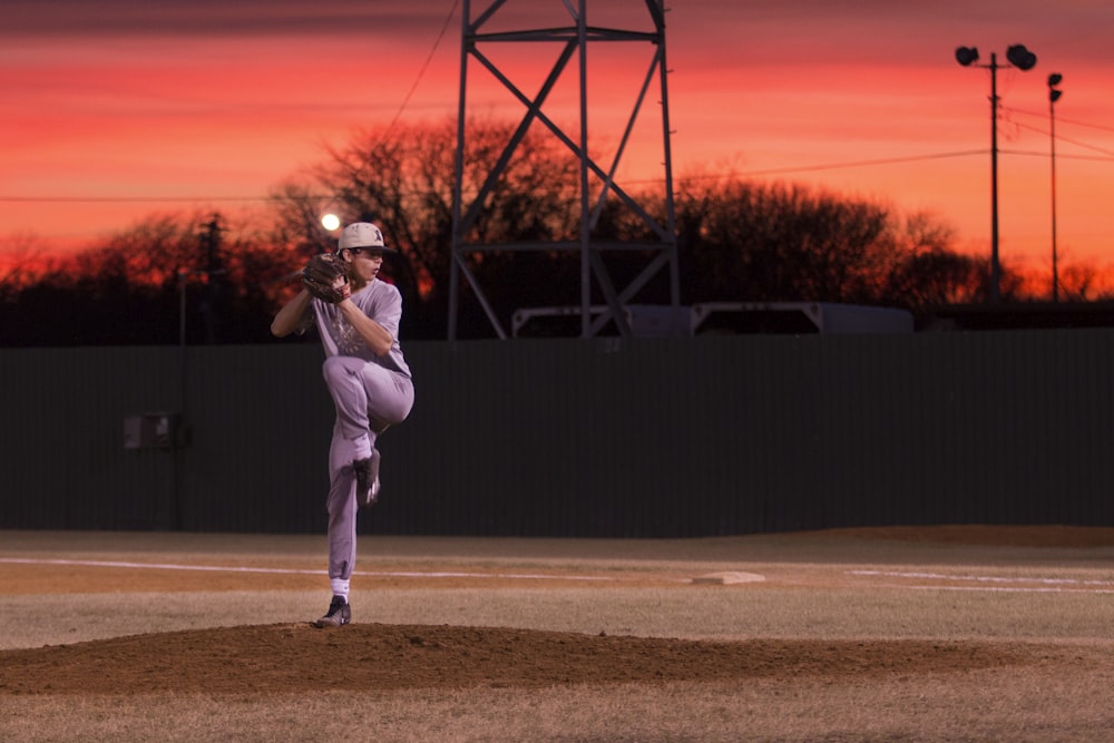 hombre lanzando béisbol durante la puesta del sol