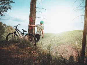 person holding onto tree while leaning towards cliff during daytime