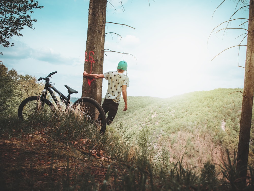 person holding onto tree while leaning towards cliff during daytime