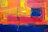 Close-up of vibrant abstract painting with bold strokes of blue, red, and gold.