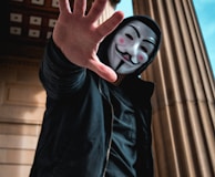 man wearing Guy Fawkes Mask standing inside building