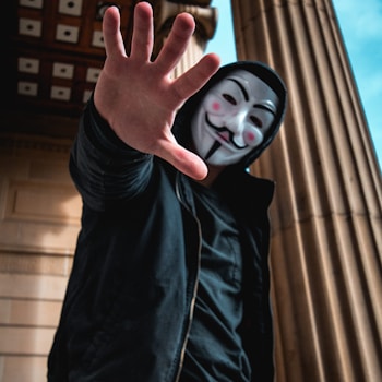 man wearing Guy Fawkes Mask standing inside building