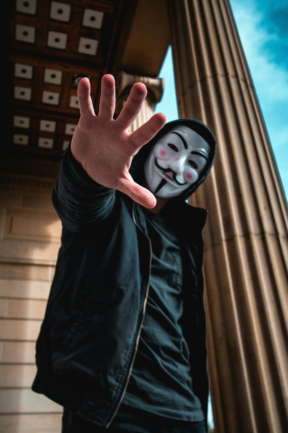 man wearing Guy Fawkes Mask standing inside building