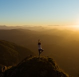 woman stretching on mountain top during sunrise