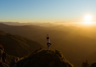 woman stretching on mountain top during sunrise