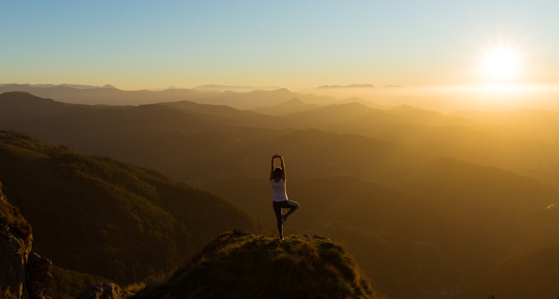 woman stretching on mountain top during sunrise