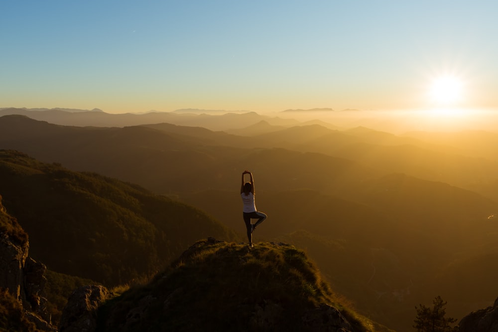 Frau, die sich während des Sonnenaufgangs auf dem Berggipfel streckt