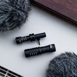 A minimalist podcast studio shot featuring high-end microphones and soft monochrome lighting.