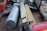A close-up view of various hand tools and measuring devices, including a folded ruler with visible numerical markings and a large metallic tool with a cylindrical grip. The tools are arranged casually on a table, suggesting a workshop or garage setting.