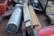 A close-up view of various hand tools and measuring devices, including a folded ruler with visible numerical markings and a large metallic tool with a cylindrical grip. The tools are arranged casually on a table, suggesting a workshop or garage setting.
