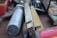 A close-up view of various hand tools and measuring devices, including a folded ruler with visible numerical markings and a large metallic tool with a cylindrical grip. The tools are arranged casually on a table, suggesting a workshop or garage setting.