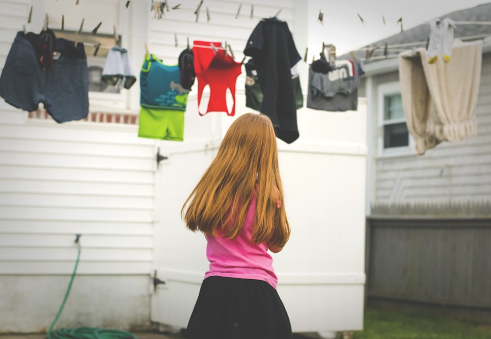 girl standing under clothes on airer at daytime