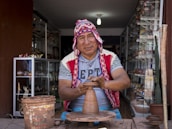 man making clay pot while sitting on chair