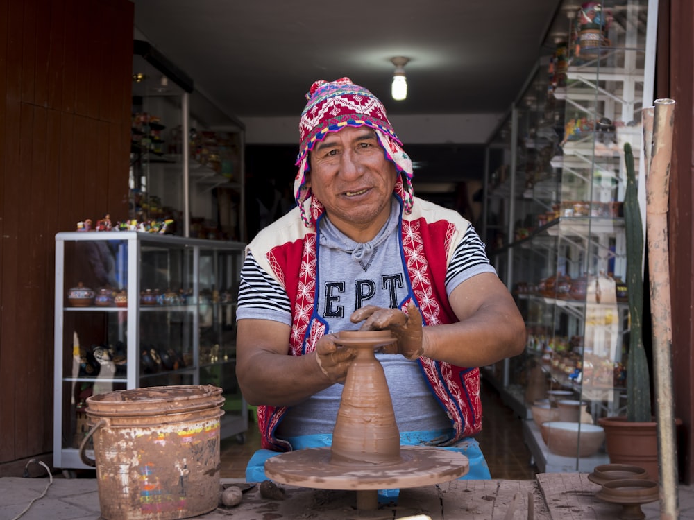 man making clay pot while sitting on chair