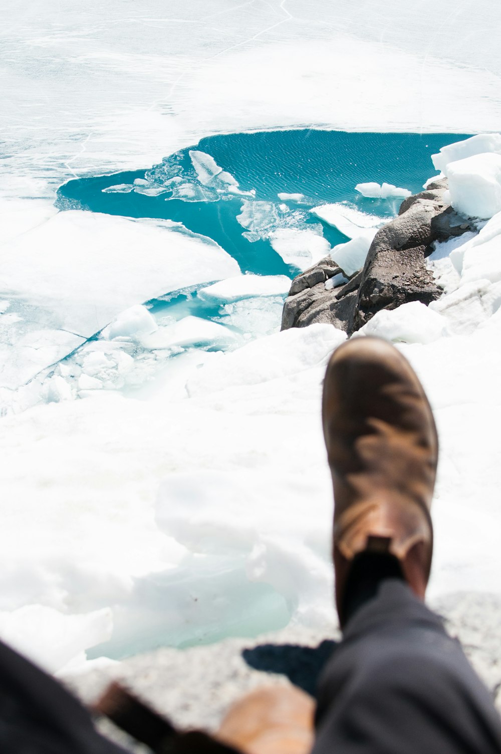 person seating on stone in front of glacier