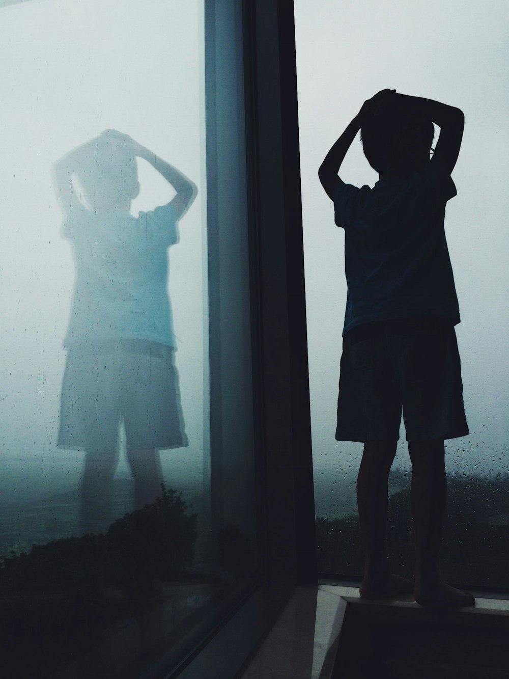 boy near clear glass window