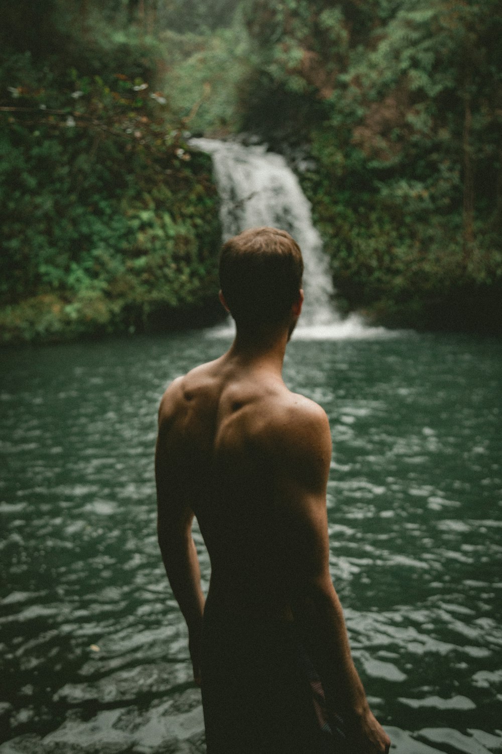 man facing waterfalls at daytime
