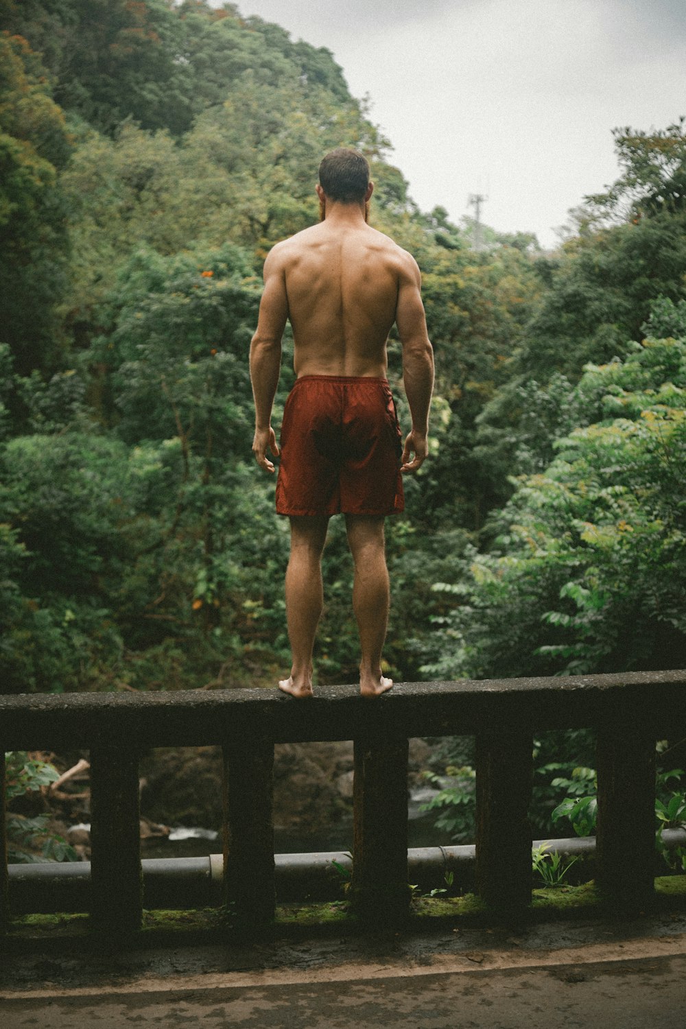 橋の端に立つ赤いショートパンツのセレクティブフォーカス写真の男