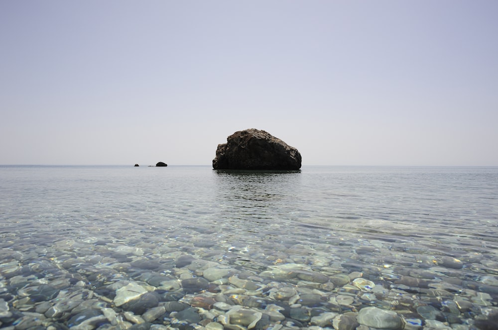 black rock formation in the middle of sea