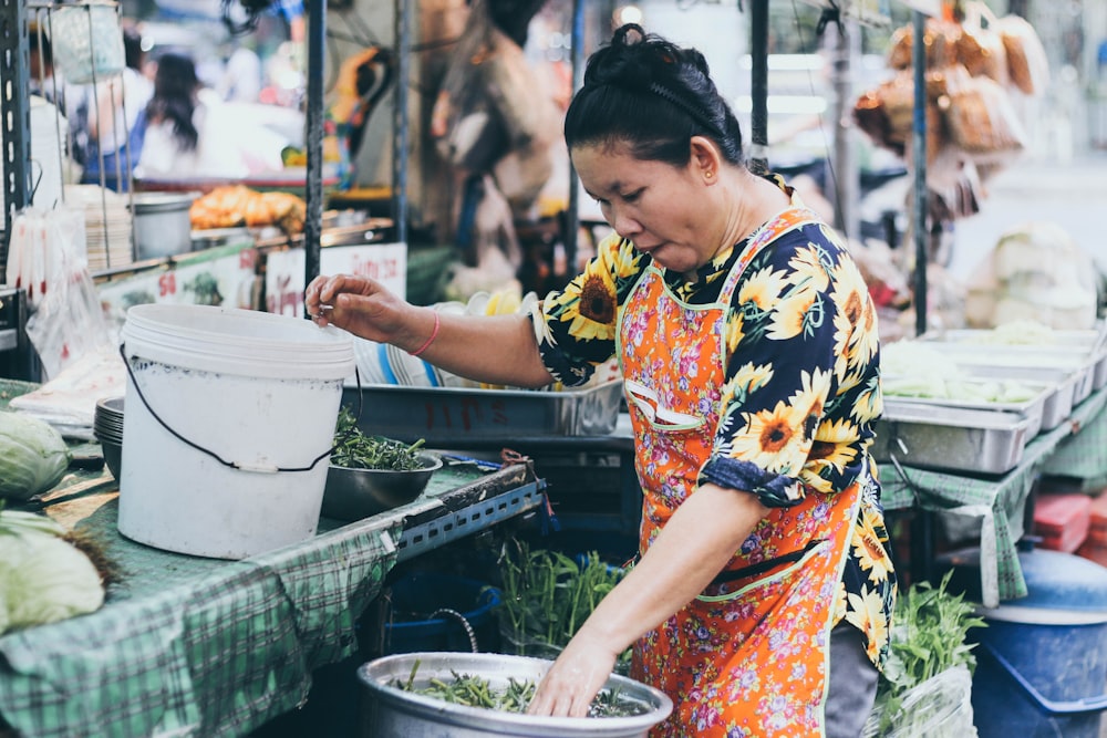 woman wearing orange floral apron holding vegetable