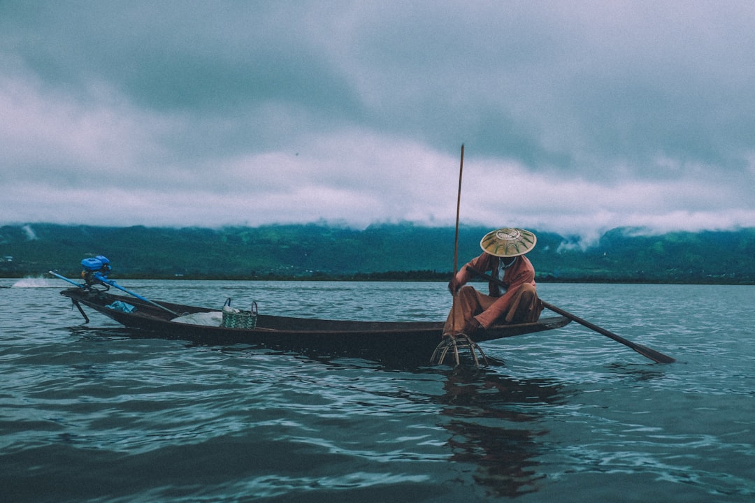 man fishing on boat under dramatic sky