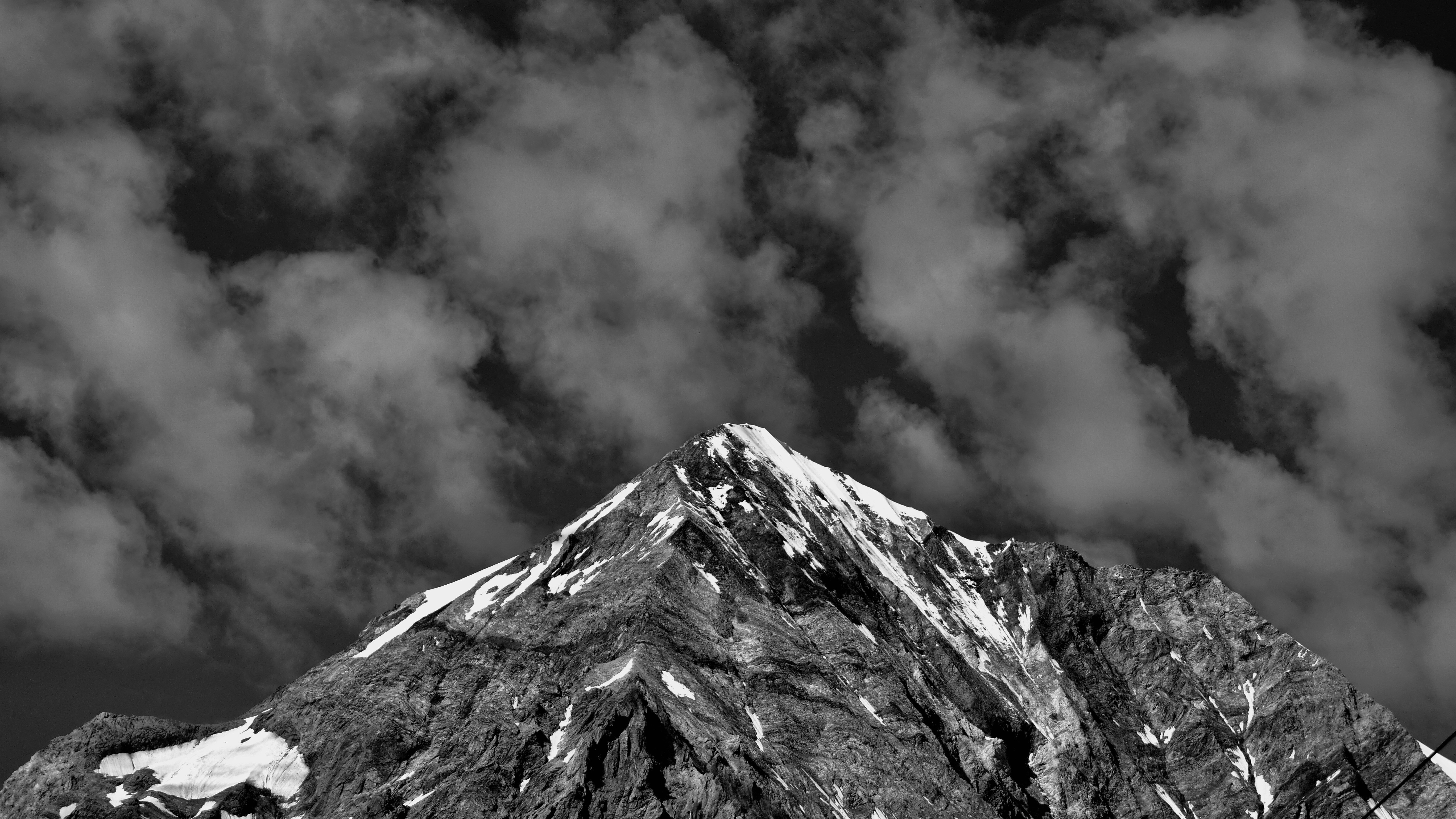 Photo en niveaux de gris d’une montagne sous un ciel nuageux
