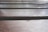 Close-up view of wooden planks with visible grain and texture, arranged horizontally. The lighting highlights the natural pattern and gloss of the wood finish.